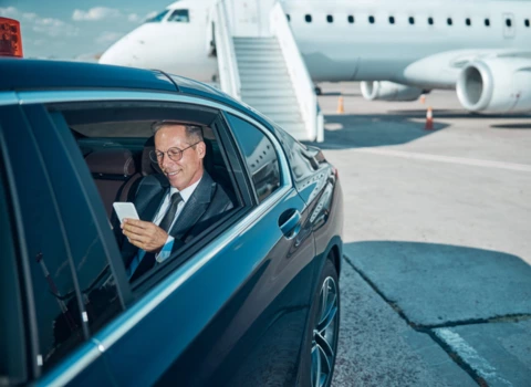 Business man sitting in a luxury black car at airport